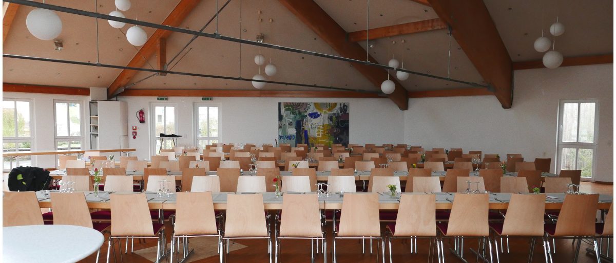 Leerer Gemeindesaal mit Stuhlreihen und Tischen